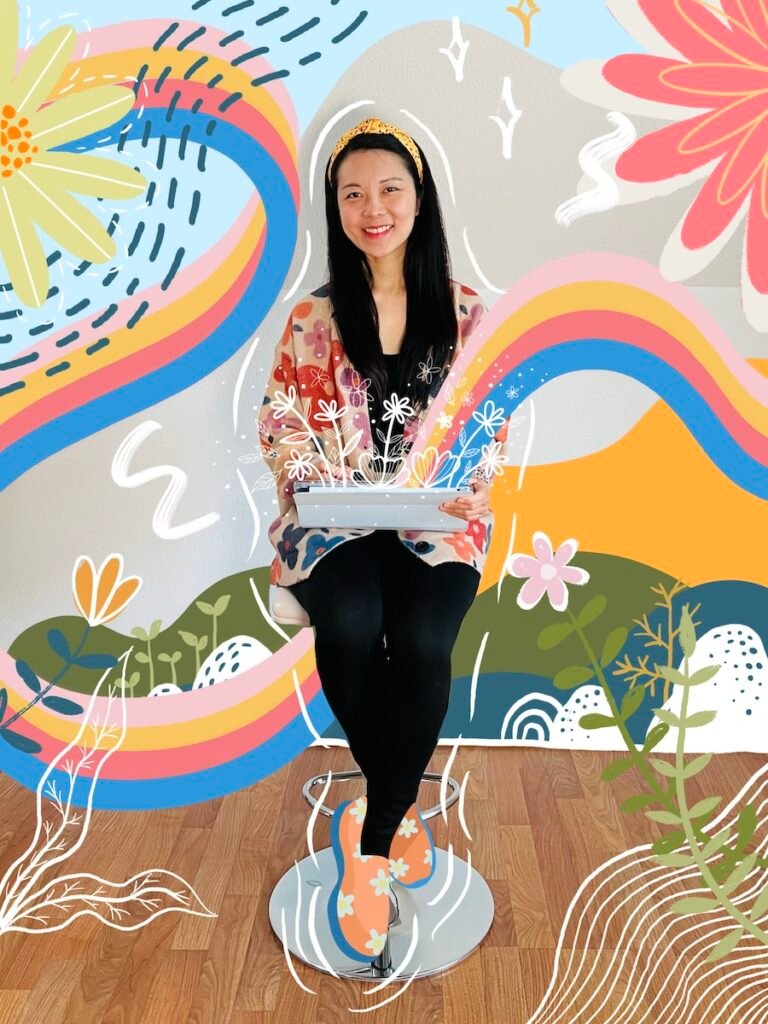 photo-2 An artist sitting on a tall chair holding an iPad. Colorful whimsical drawing surrounding the artist and floral emerging from the iPad.